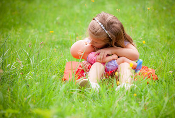 beautiful little girl with doll on the nature