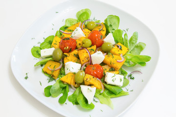 Warm salad with roasted pumpkin and cherry tomatoes with homemade cheese and olives, selective focus