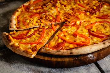 Pizza with tomatoes and corn isolated on wood background