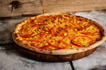 Pizza with tomatoes and corn isolated on wood background