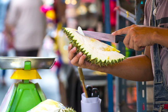 A fruits shop owner is using knife to peel durian in the wet market in Singapore. After peeling durian are packaged into fresh to-go, ready to eat, convenience packs and sell locally