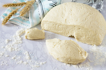 Fresh dough and ears on a stone gray background, dough in the br