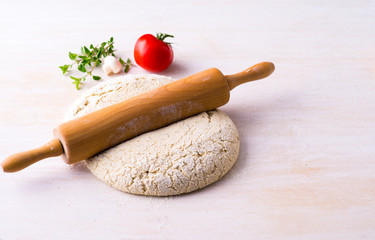 A rolling pin on pizza dough