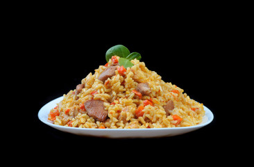 pilaf with meat and carrots on white plate and black background