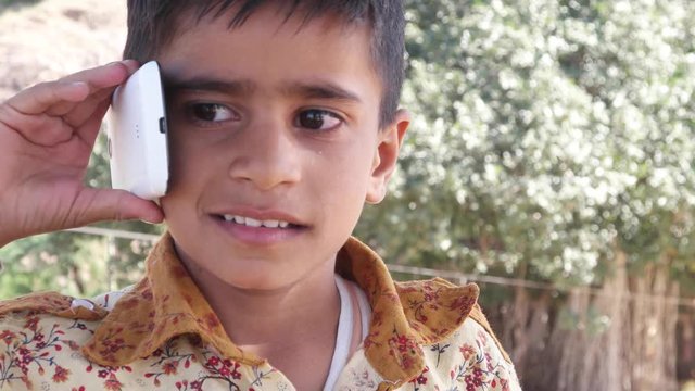 Lovely little Indian boy talking on a cell phone mobile 