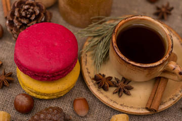 Cup of coffee, macaroons, cookies, walnuts, hazelnuts, cinnamon sticks, star anise, cone, candle, fir branch on sackcloth fabric