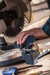 Senior carpenter cutting wooden plank with circular saw in his workshop.