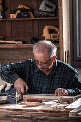 Senior carpenter taking measurement on a wooden plank in workshop