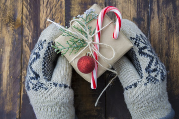 Christmas gift box in hands in warm mittens