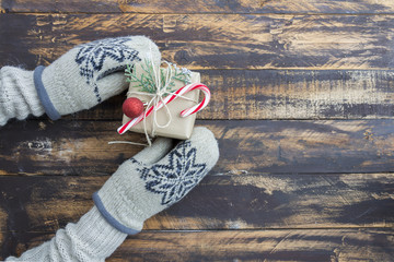 Christmas gift box in hands in warm mittens