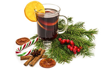 Mulled wine in glass with cinnamon stick, christmas tree and candy isolated on a white