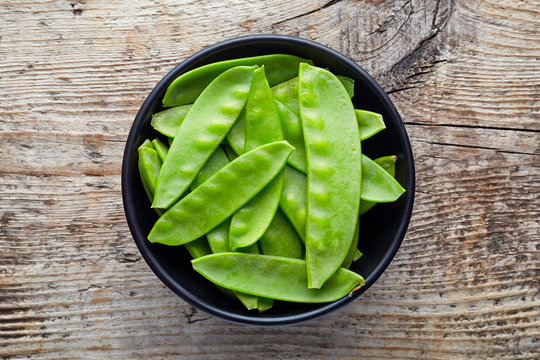 Bowl Of Snow Peas On Wooden Table, From Above