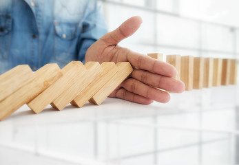 Problem Solving,Close up view on hand of business woman stopping falling blocks on table for concept about taking responsibility...