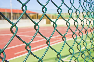 Wire metal mesh against a tennis court - concept image