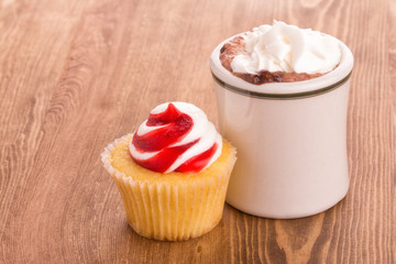 Strawberry cupcake with a cup of hot chocolate on wooden tabletop - with a slight softening filter for a nostalgic effect