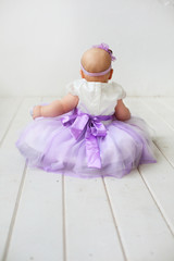 little baby in dress sitting on the floor