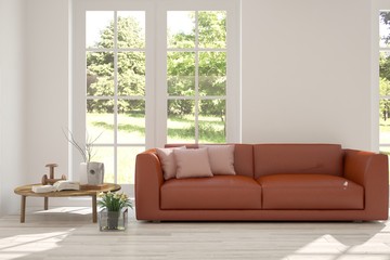 White room with sofa and green landscape in window. Scandinavian interior design