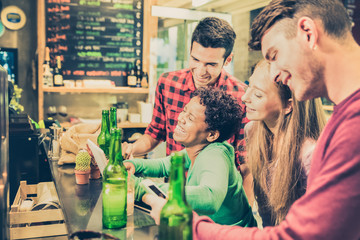 Multiracial friends drinking beer and having fun at cocktail bar restaurant - Friendship concept with people enjoying time together - Vintage lomo filter with vignetting and focus on laughing girl