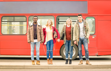 Multiracial friends group crossing road ahead, traditional red bus, Autumn or winter, concept of social life with young people hanging out together