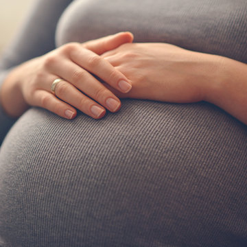 Woman holding her hands on stomach - Pregnancy concept