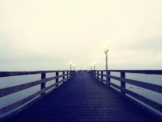 Fototapeta na wymiar Autumn dark mist on wooden pier above sea. Depression, dark atmosphere.
