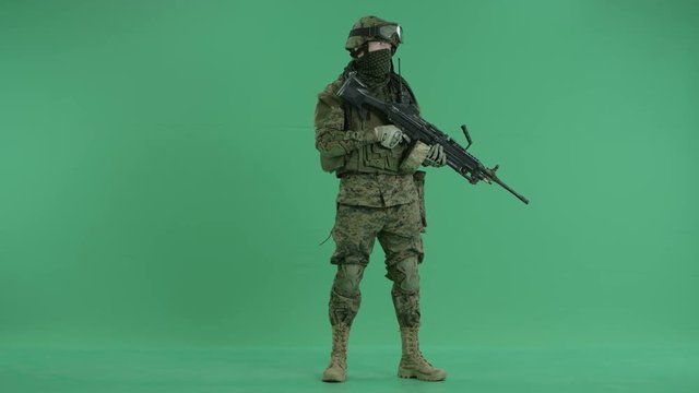 serviceman standing with weapon and looking at side at green screen