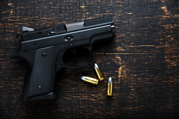 Gun and ammunition on dark wooden table. top view