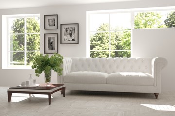 White room with sofa and green landscape in window. Scandinavian interior design