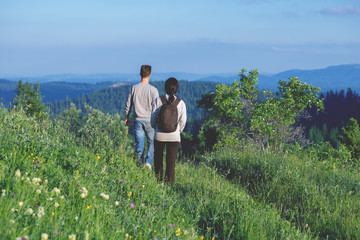 Fototapeta na wymiar Young couple with backpacks hiking in the mountains and enjoying valley view.Colored photo