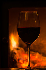 Glowing fire with a glass of red wine