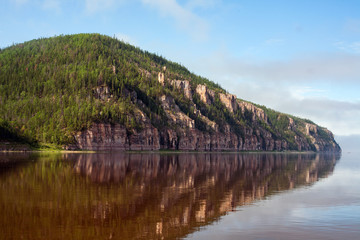 Rocky river bank and its reflection on the water. Lena river. Yakutia. Russia.