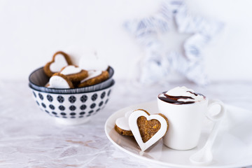 biscotti decorati in primo piano, disposti in ciotole. Tazza con cioccolata e panna; foto orizzontale 