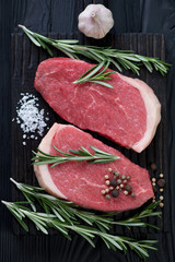 Above view of two uncooked beef medallion steaks with seasonings