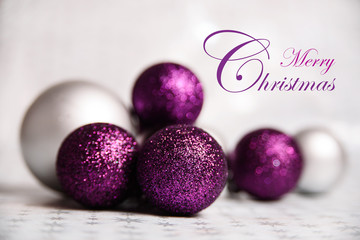 Purple Sparkling and Silver Christmas balls Close-up on a soft focus light background. horizontally holiday banner with Marry Christmas text