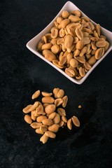 Tray with salted peanuts on heap and in white bowl