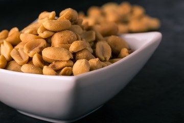 White bowl full of salted peanuts