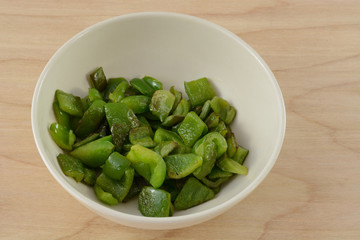 Grilled chopped green bell peppers in white bowl
