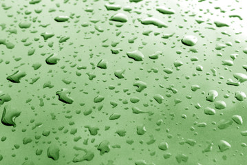 Rain drops on green metal surface with blur effect