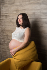 Pregnant woman in a white blouse in the chair