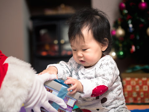 Asian baby girl wearing Christmas jumper with her Christmas toy