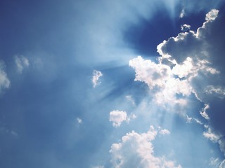 Naklejka na ściany i meble Light ray from sun behind cloud in the blue sky