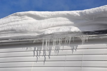 Icicles and thick snow over the roof of the house