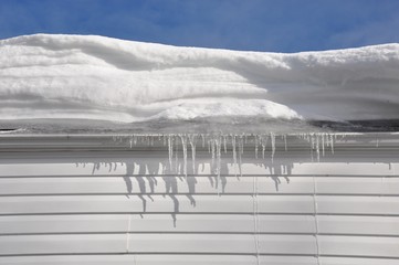 Thick snow and icicles in house roof