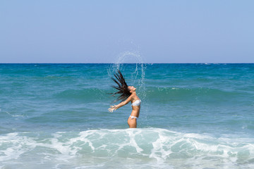 Tanned brunette in white bikini enjoying summer on the beach