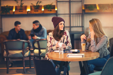 Two friends enjoying coffee together in a coffee shop as they si