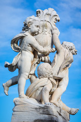 Statue of cherubs holding a shield with the Cross of Pisa on it in Pisa, Italy