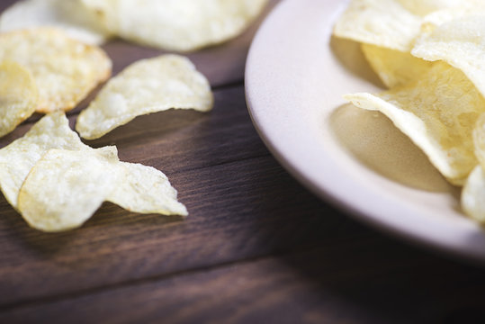 Close-up of a plate with chips and several potatoes on the table