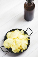 Dish with chips, beer bottle  on pale gray table. Vertical studio shot