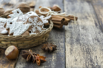 Basket with ginger cookies, nuts and cinnamon on dark wooden background