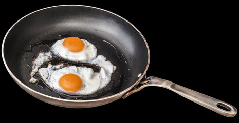 Pair of Sunny Side Up Fried Eggs In Old Heavy Duty Steel Frying Pan Isolated On Black Background